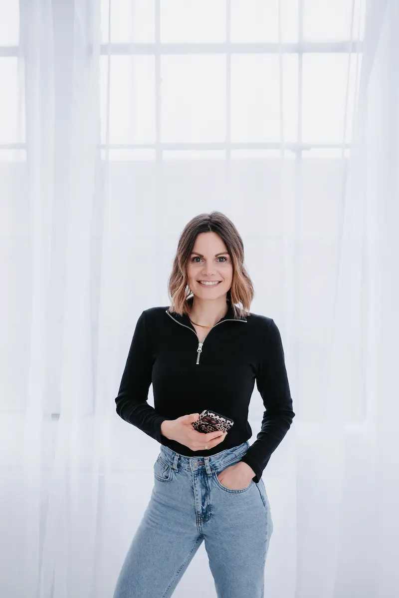 alena-scheffler-social-media-expertin-hochzeitsdienstleister-nrw.webp Alena Scheffler, Social Media Strategin für Hochzeitsdienstleister, im hellen Studio mit Smartphone in der Hand