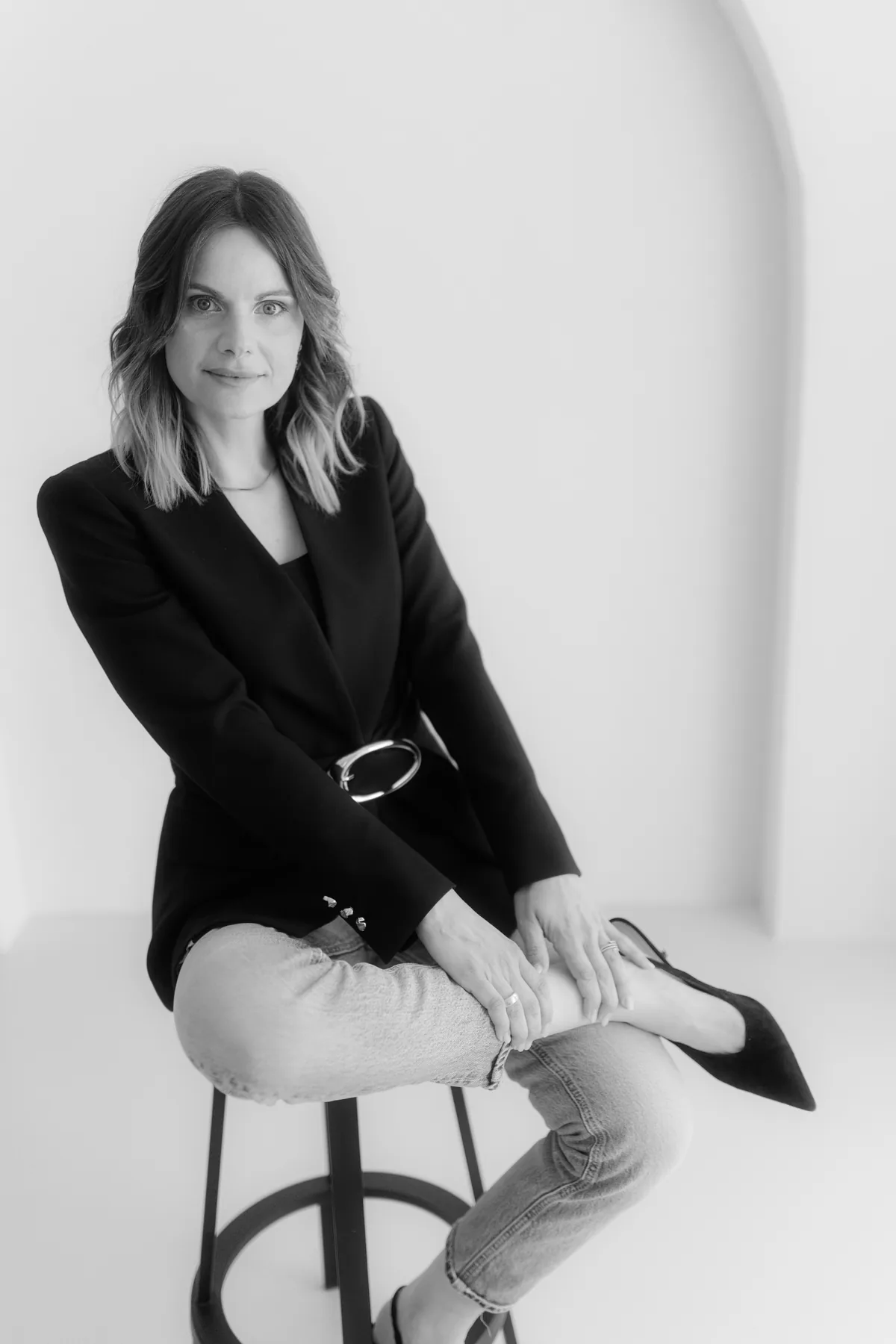 Alena Scheffler sitzt im Blazer auf einem Hocker, KI-Sichtbarkeit für Hochzeitsdienstleister